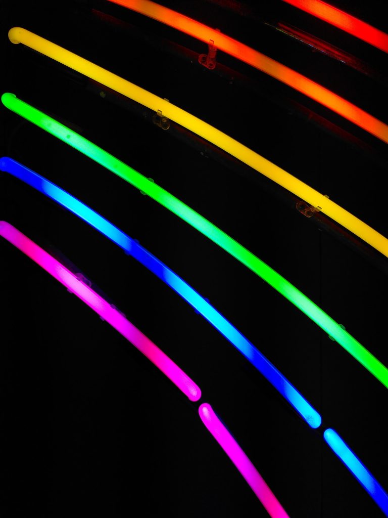 rainbowcolored neonlights infront of a dark background
